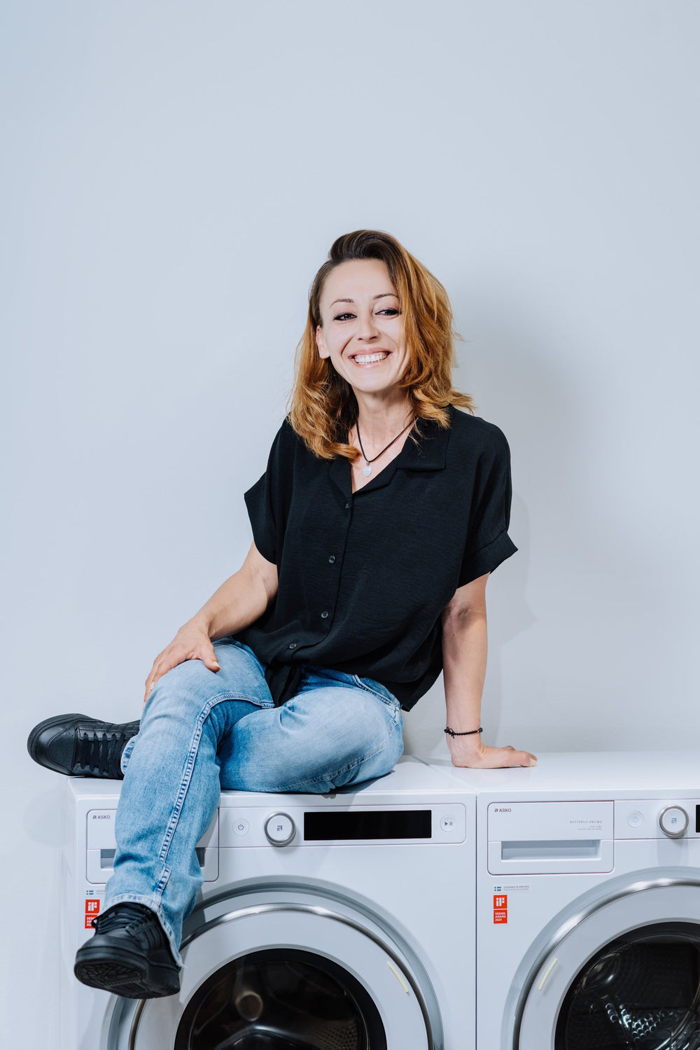 Lirjana Marques sitzt im Experience Center in Balsthal auf einer ASKO Waschmaschine